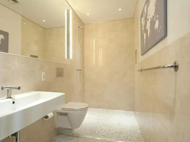 full bathroom featuring tile walls, toilet, walk in shower, a sink, and tile patterned flooring