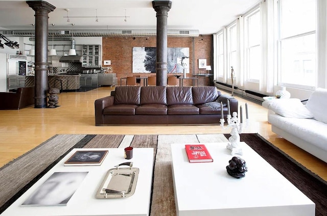 living room with a wood stove, wood finished floors, and a baseboard heating unit