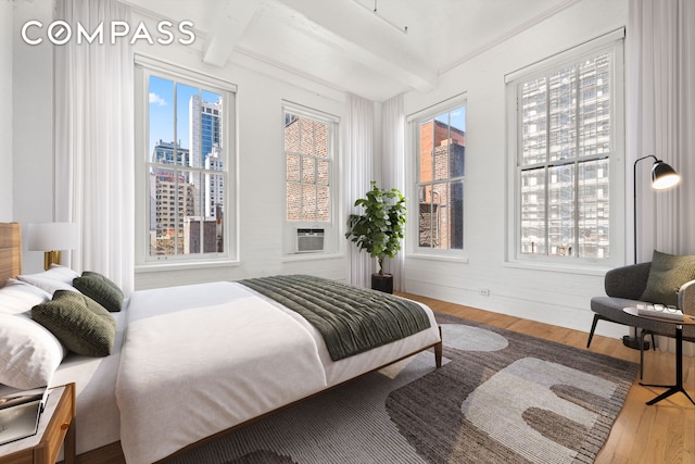 448 W 37th St Unit 6H, New York City, NY 10018 - bedroom with a view of city, beam ceiling, wood finished floors, and cooling unit