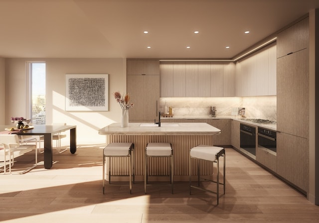 249 E 62nd St Unit 23A, New York City, NY 10065 - kitchen featuring wall oven, a sink, light wood-style flooring, modern cabinets, and recessed lighting