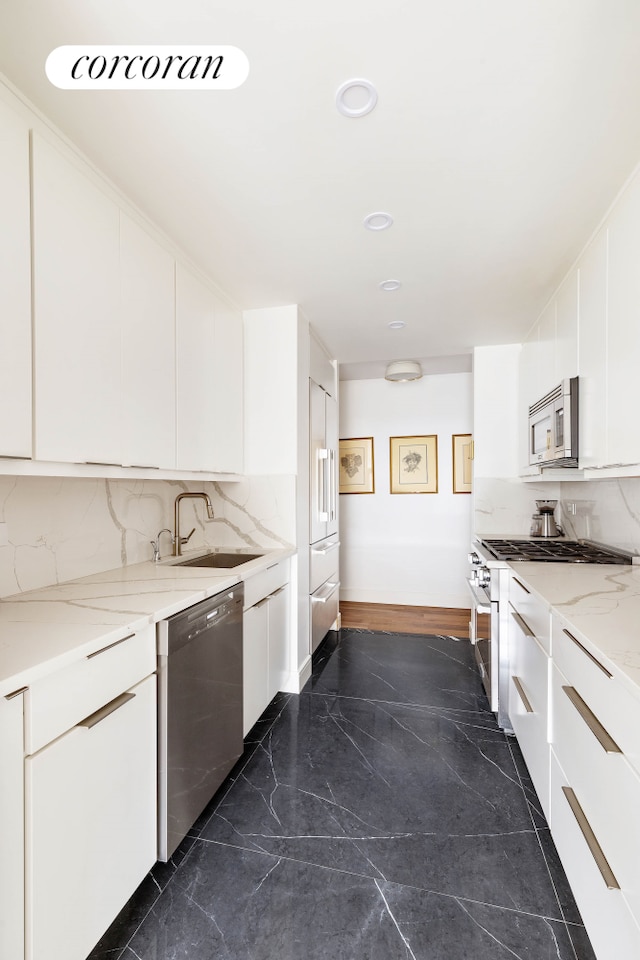 kitchen with appliances with stainless steel finishes, a sink, white cabinets, and recessed lighting