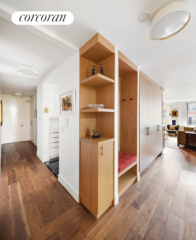 hallway with dark wood-style flooring, baseboards, and stairs