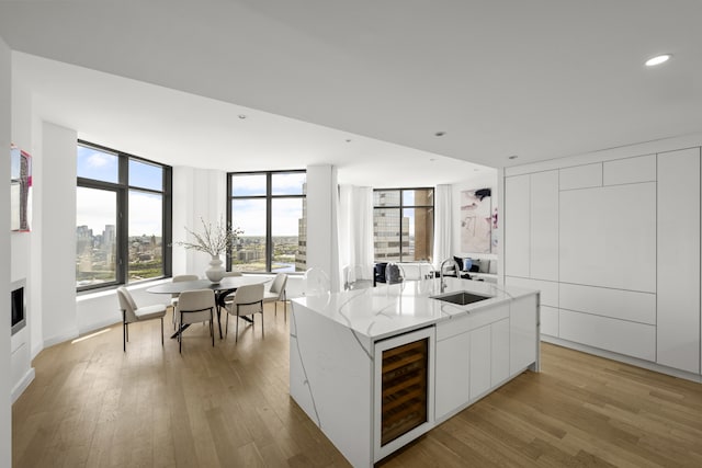 75 Wall St Unit Phd2, New York City, NY 10005 - kitchen with beverage cooler, modern cabinets, light wood finished floors, light stone counters, and recessed lighting