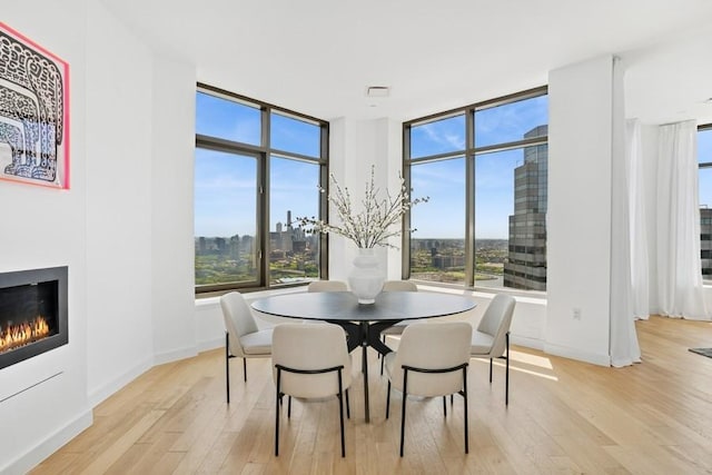 75 Wall St Unit Phd2, New York City, NY 10005 - dining area with light wood finished floors, a glass covered fireplace, and a wall of windows
