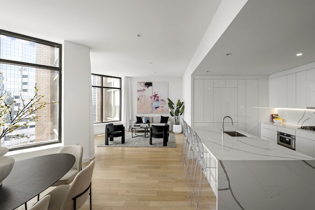 75 Wall St Unit Phd2, New York City, NY 10005 - kitchen with modern cabinets, white cabinetry, light wood finished floors, oven, and light stone countertops