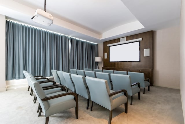 home theater room with light colored carpet and a tray ceiling