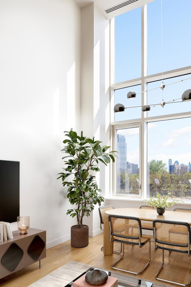 living area featuring a towering ceiling, wood finished floors, and baseboards
