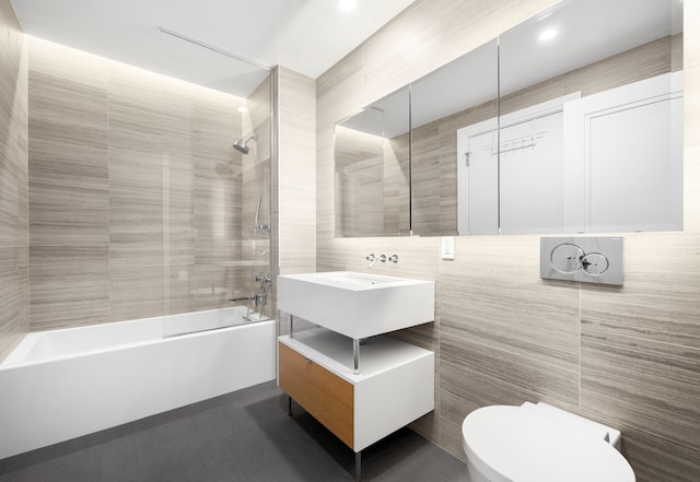 318 E 81st St Unit 1, New York City, NY 10028 - full bathroom with tile walls, toilet, washtub / shower combination, and vanity