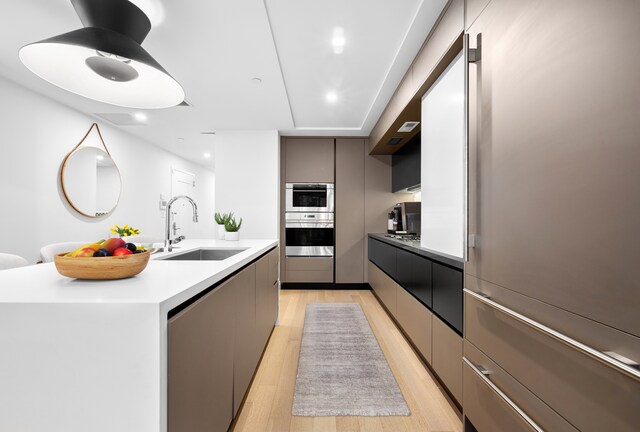 318 E 81st St Unit 1, New York City, NY 10028 - kitchen featuring modern cabinets, a sink, light wood finished floors, stainless steel appliances, and a kitchen island with sink