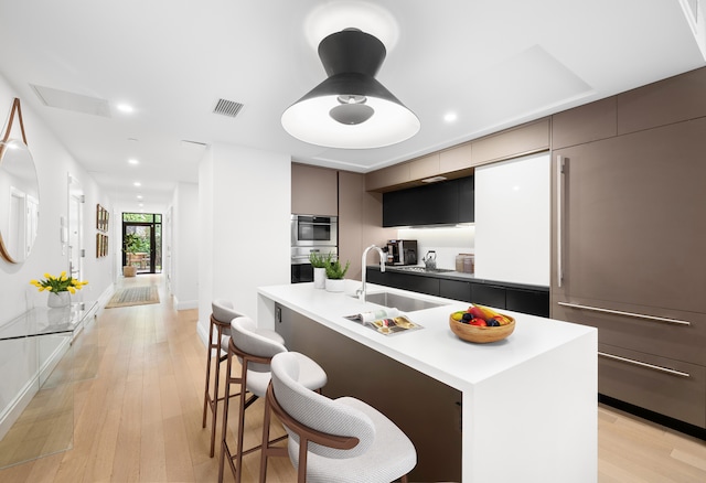 318 E 81st St Unit 1, New York City, NY 10028 - kitchen with modern cabinets, a kitchen bar, a sink, light wood-style floors, and recessed lighting