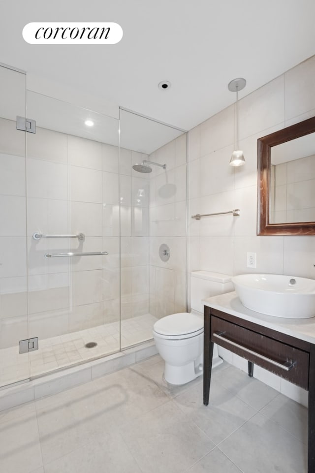 full bathroom featuring tile patterned flooring, a shower stall, toilet, vanity, and tile walls