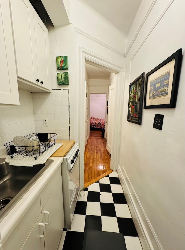 kitchen featuring tile patterned floors, white cabinets, backsplash, and light countertops