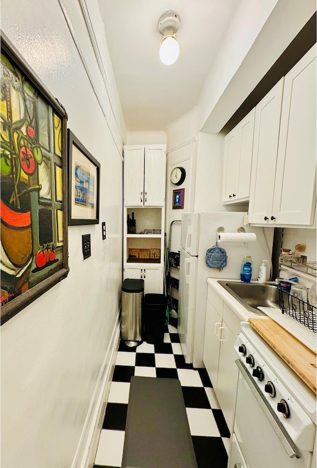 kitchen featuring dark flooring, white cabinets, light countertops, and a sink