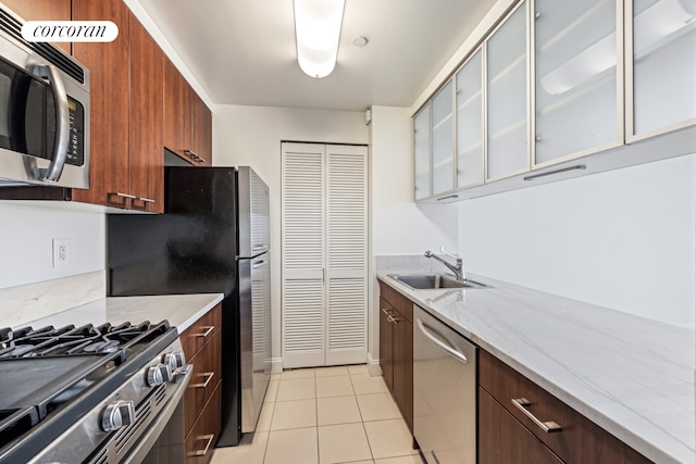 kitchen with stainless steel appliances, modern cabinets, light tile patterned flooring, glass insert cabinets, and light stone countertops