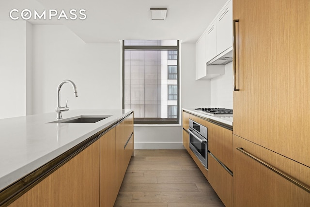 319 Schermerhorn St Unit 6B, New York City, NY 11217 - kitchen with stainless steel oven, light countertops, light wood-type flooring, white cabinets, and gas cooktop
