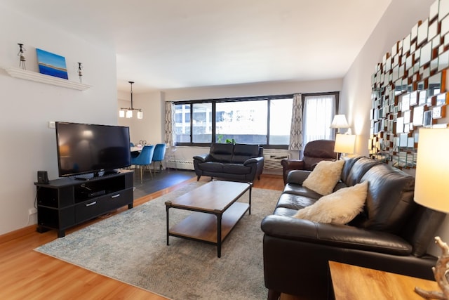 living area featuring a baseboard radiator, wood finished floors, baseboards, and a chandelier
