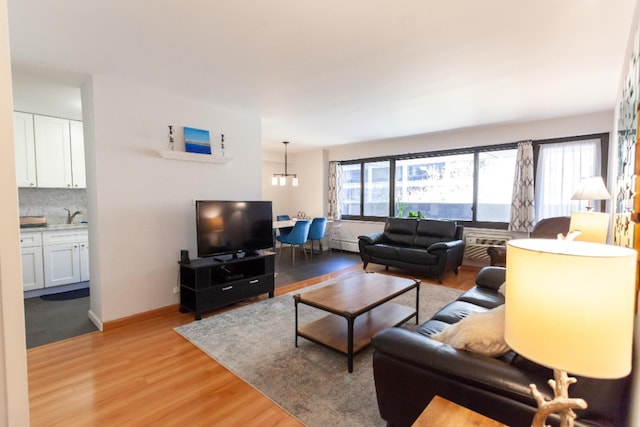 living room featuring a baseboard radiator, light wood-style flooring, and baseboards