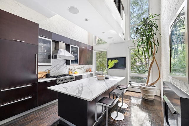 262 W 25th St, New York City, NY 10001 - kitchen with wall chimney range hood, modern cabinets, a kitchen breakfast bar, a center island, and dark wood-style floors