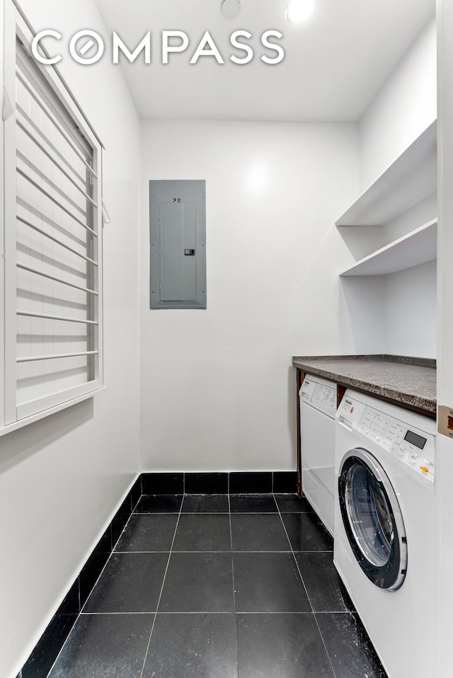 washroom with electric panel, independent washer and dryer, dark tile patterned flooring, and baseboards