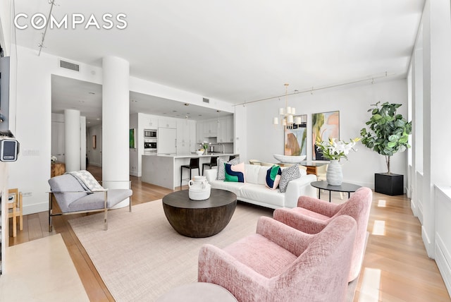living area featuring light wood-type flooring and a chandelier