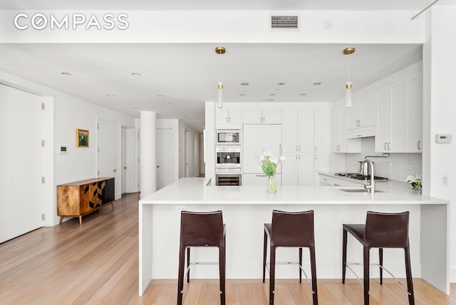 kitchen featuring a peninsula, white cabinets, a kitchen bar, and light wood-type flooring