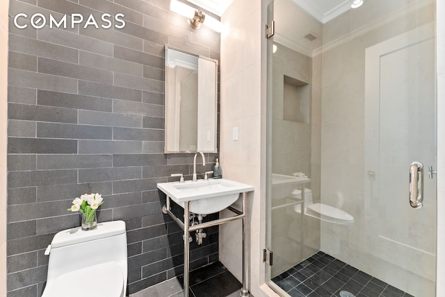 bathroom with toilet, tile walls, crown molding, a stall shower, and a sink