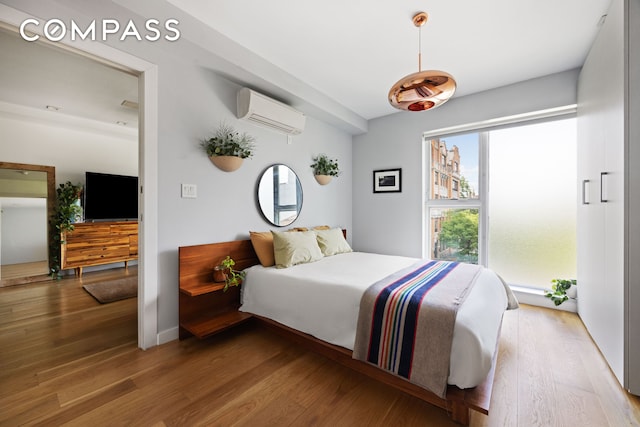 bedroom with wood finished floors and an AC wall unit
