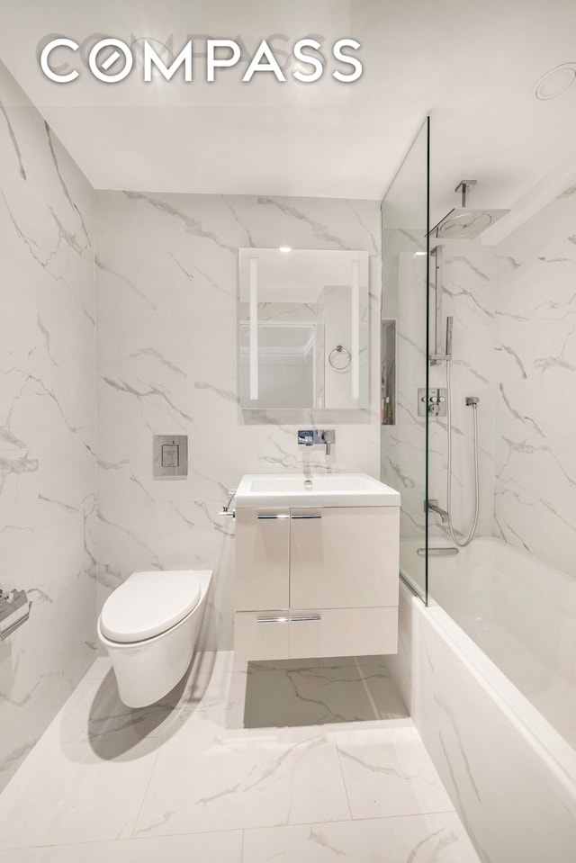 full bath with marble look tiles, toilet, vanity, a combined bath / shower with rainfall shower, and tile walls