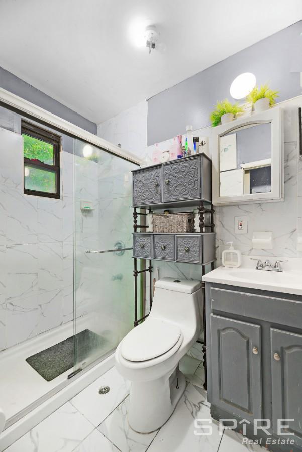 13 Suydam Place, New York City, NY 11233 - full bathroom featuring marble look tile flooring, toilet, vanity, and a marble finish shower