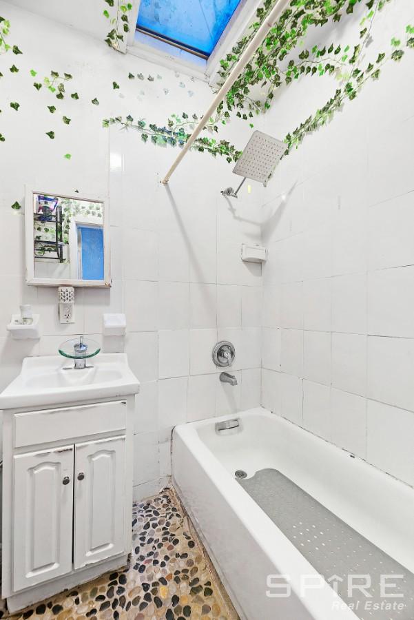 13 Suydam Place, New York City, NY 11233 - bathroom with a skylight, vanity, shower / tub combination, and tile walls
