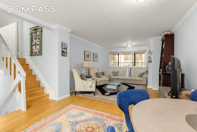 living area featuring stairway, wood finished floors, crown molding, and baseboards