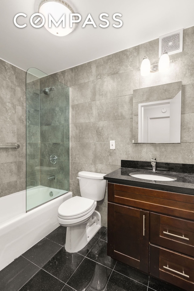 full bathroom featuring toilet, vanity, shower / bath combination, granite floors, and tile walls