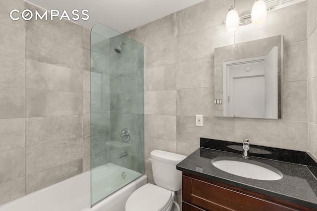 bathroom featuring tile walls, vanity, toilet, and shower / washtub combination