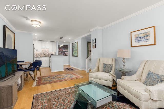 living area featuring light wood-style flooring, ornamental molding, recessed lighting, and baseboards