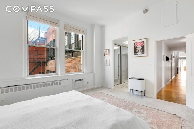 35 E 12th St Unit 8C, New York City, NY 10003 - bedroom with radiator heating unit, a wall mounted air conditioner, light carpet, and baseboards