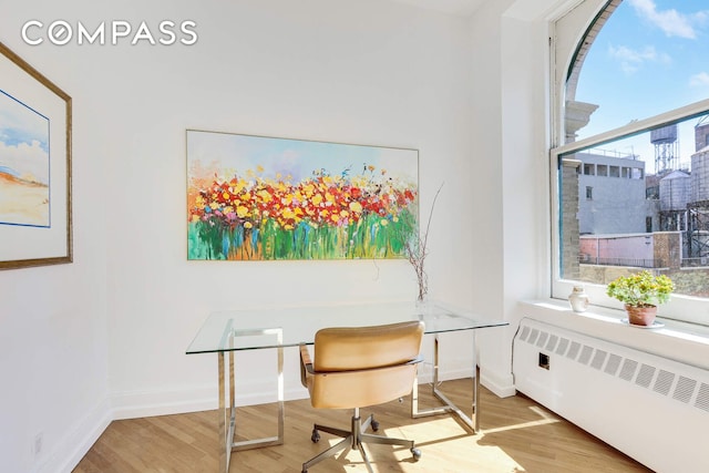 35 E 12th St Unit 8C, New York City, NY 10003 - home office featuring radiator heating unit, wood finished floors, and baseboards