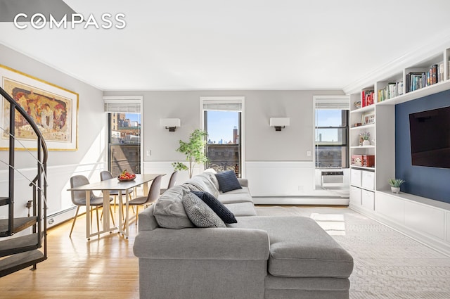 living area featuring a baseboard heating unit, a wainscoted wall, and light wood finished floors
