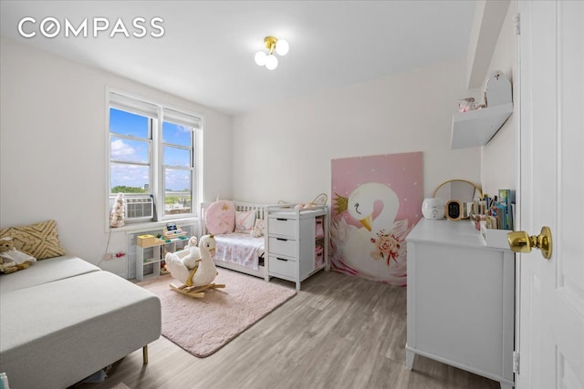 bedroom featuring light wood finished floors and cooling unit