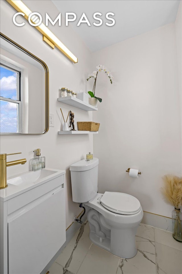 bathroom featuring marble finish floors, toilet, and vanity