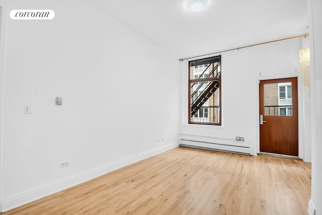 124 W 24th St Unit 4B, New York City, NY 10011 - unfurnished room with a baseboard radiator, wood finished floors, and healthy amount of natural light
