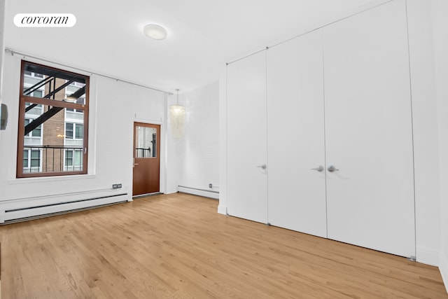 124 W 24th St Unit 4B, New York City, NY 10011 - unfurnished bedroom featuring baseboard heating, a baseboard heating unit, and light wood finished floors
