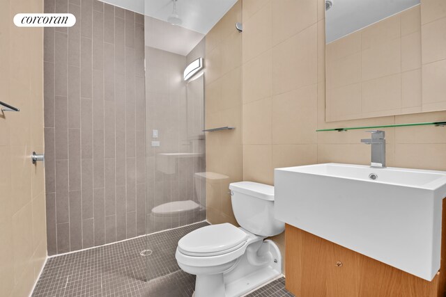 124 W 24th St Unit 4B, New York City, NY 10011 - full bathroom featuring tile walls, tiled shower, vanity, and tile patterned floors