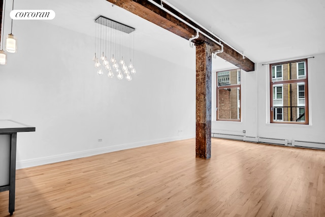 124 W 24th St Unit 4B, New York City, NY 10011 - unfurnished living room featuring wood finished floors, a baseboard radiator, and track lighting