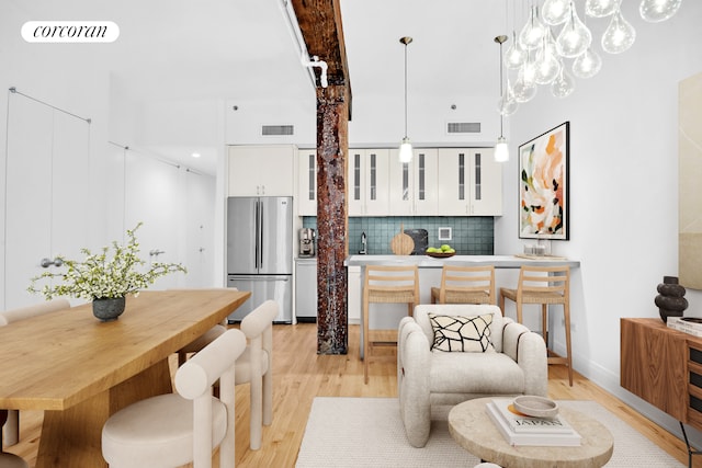 124 W 24th St Unit 4B, New York City, NY 10011 - kitchen featuring freestanding refrigerator, light wood-style flooring, backsplash, white cabinetry, and glass insert cabinets