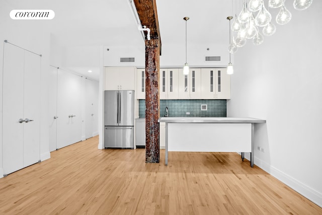 124 W 24th St Unit 4B, New York City, NY 10011 - kitchen with freestanding refrigerator, decorative backsplash, light wood-style floors, and white cabinets