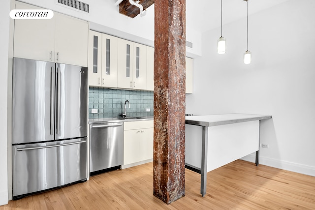 124 W 24th St Unit 4B, New York City, NY 10011 - kitchen with appliances with stainless steel finishes, a sink, light countertops, white cabinetry, and tasteful backsplash