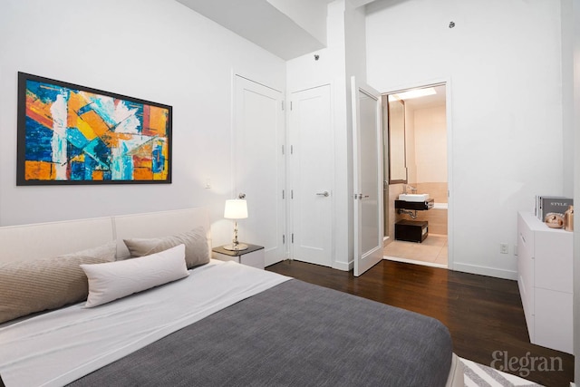 bedroom with wood finished floors, ensuite bathroom, and baseboards
