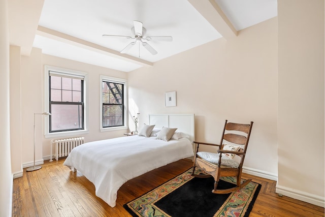 bedroom with radiator, wood finished floors, baseboards, and a ceiling fan