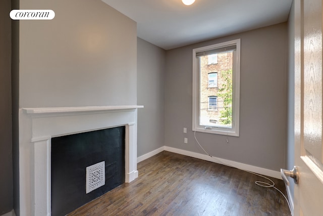 unfurnished living room featuring dark wood-type flooring, a fireplace, and baseboards