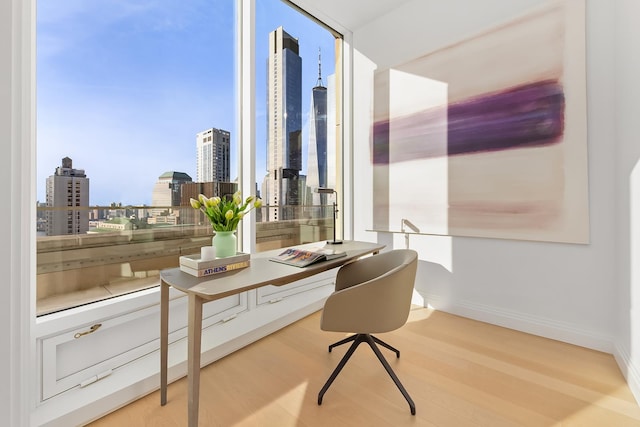 office area with a view of skyline, wood finished floors, floor to ceiling windows, and baseboards